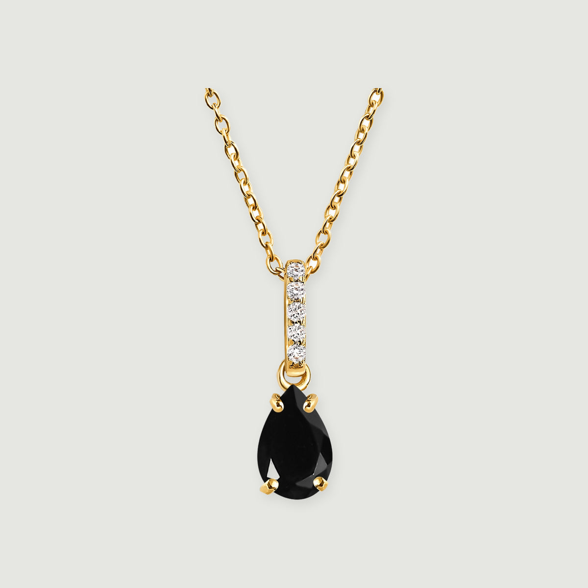 A yellow gold vermeil necklace with black onyx and a five-stone diamond bail is centered against light gray.