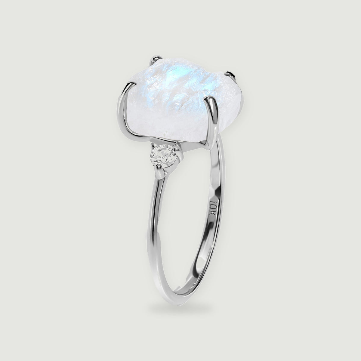 The white gold ring stands upright, revealing the raised moonstone setting and slim curved band.