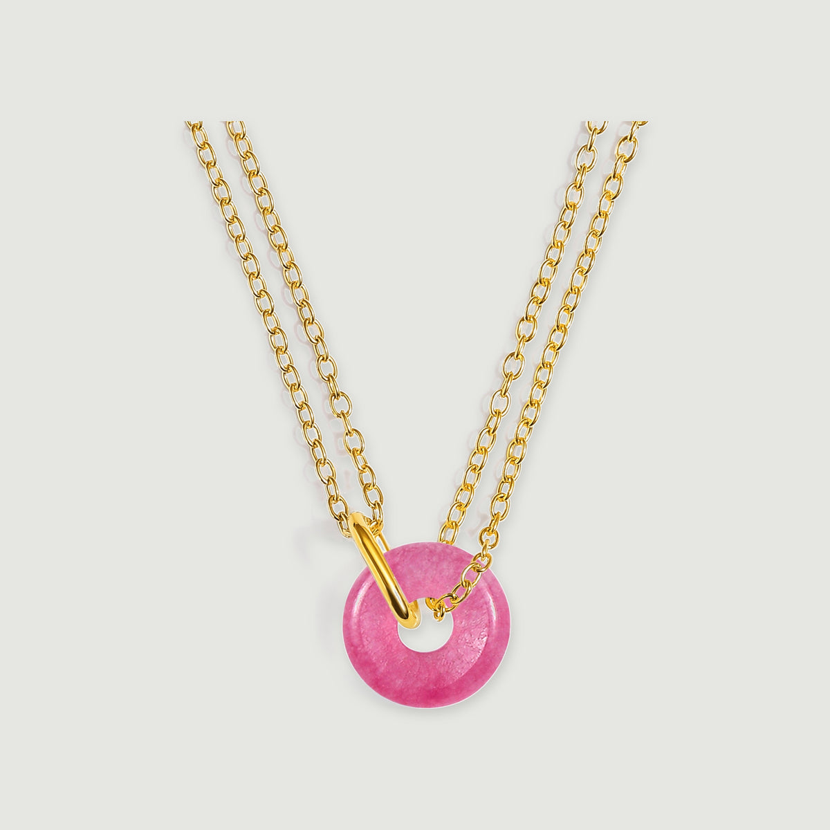 A polished pink quartz circle hangs from two yellow gold chains against a light gray background.