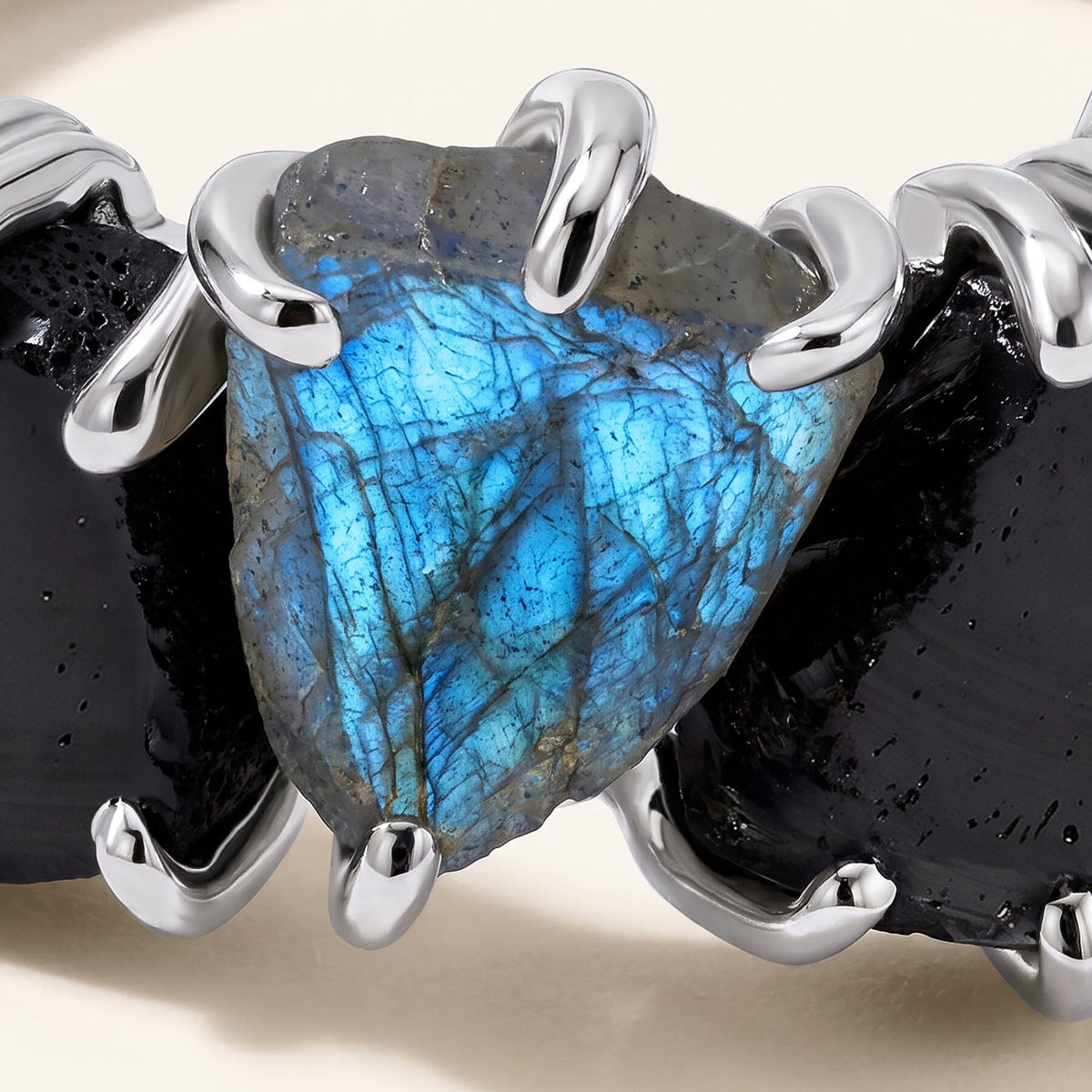 The central blue labradorite sits between two black obsidian stones in curved silver-tone prongs.
