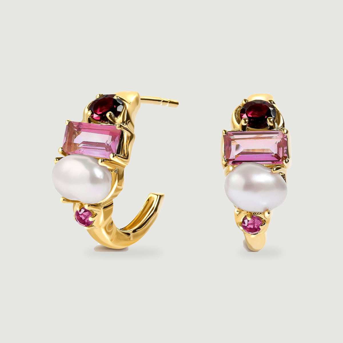 A yellow gold-tone earring pair shows its open hoop curves, white pearls and pink gemstone settings.