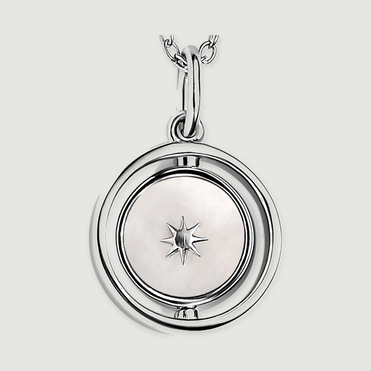 A close view of the silver pendant reveals a pale mother-of-pearl disc, an eight-point star and the open circular frame.