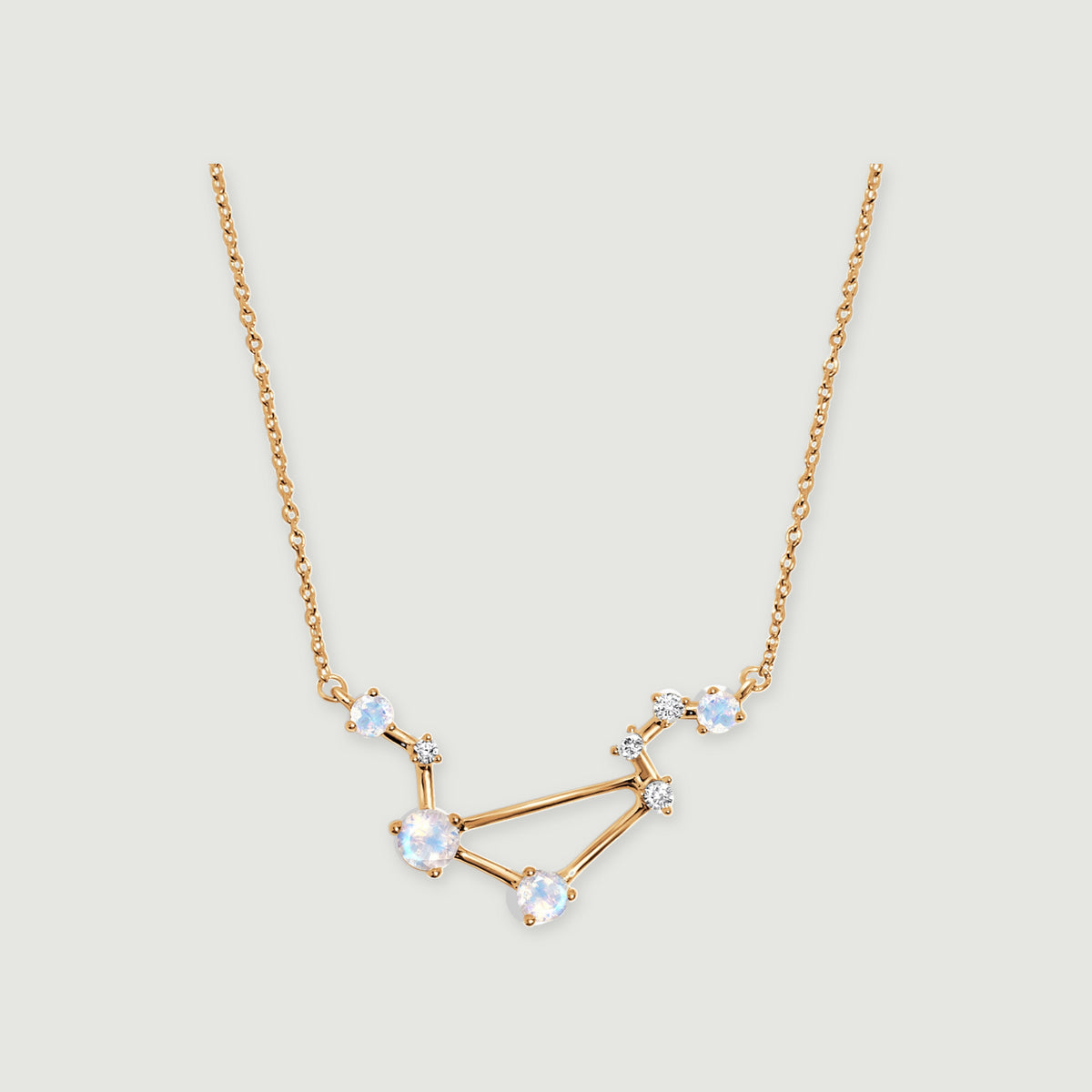A yellow gold vermeil necklace displays an angular open pendant and fine chain against a soft gray backdrop.