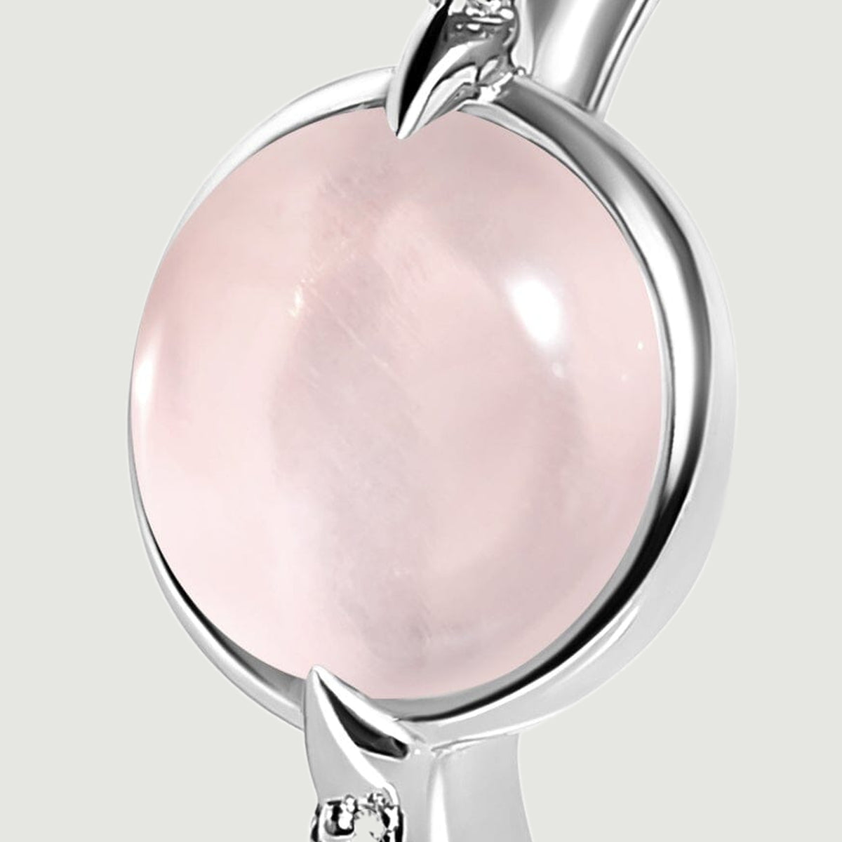 A close view shows the silver setting around the pink cabochon and a pointed prong beside a clear accent.