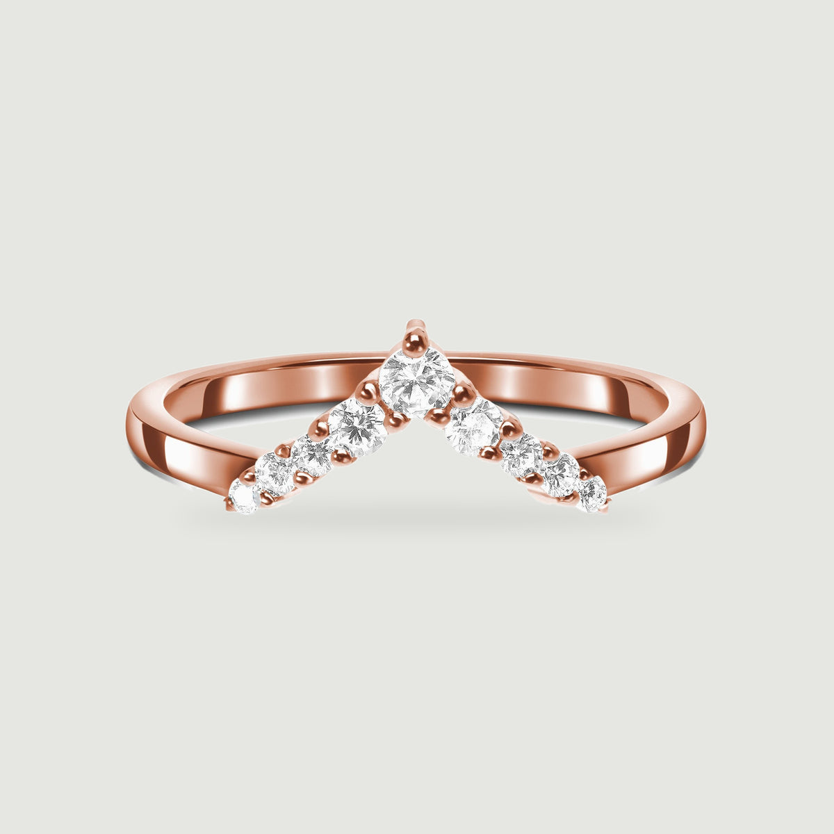 A rose gold chevron band displays clear faceted stones above a soft contact shadow.