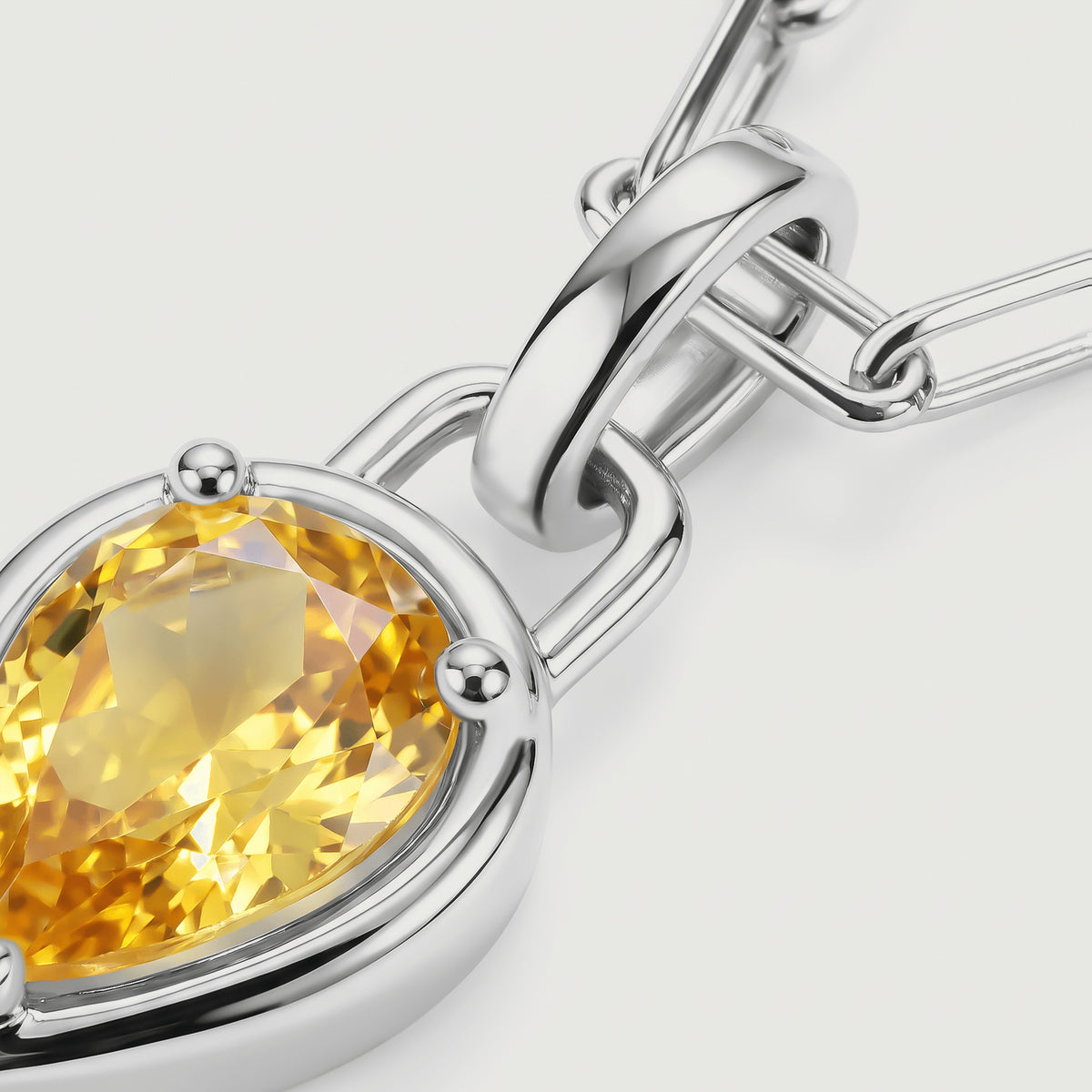 The silver-coloured pendant connector and rounded prongs sit beside sparkling yellow citrine facets.