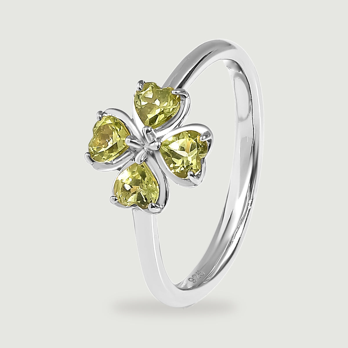 A side view reveals the polished silver band beneath four green heart-shaped gemstones.