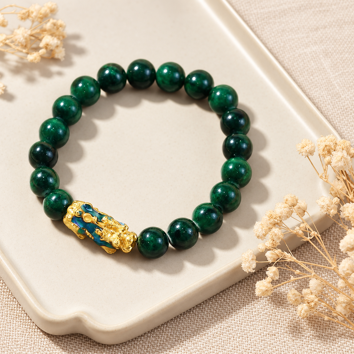 Jade bead and PiXiu bracelet arranged on a pale tray.
