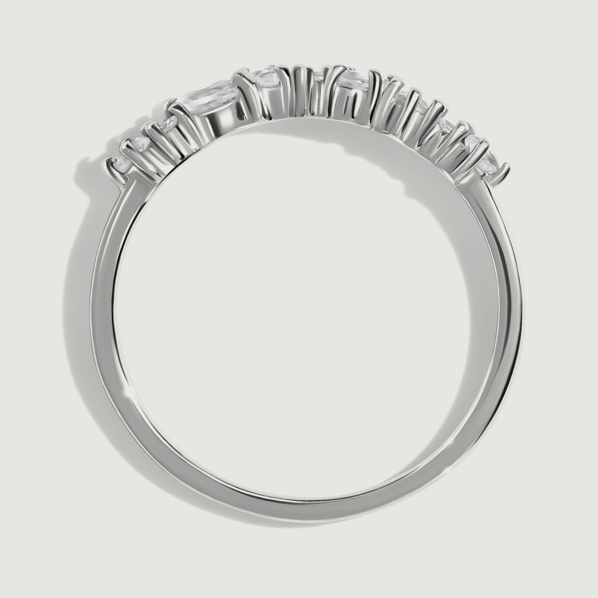 The side of a silver ring reveals raised prongs and a slim rounded band.