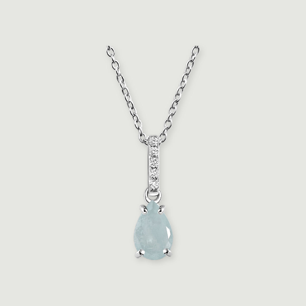 A silver chain frames a pale blue pear-shaped stone beneath a narrow row of round clear stones on light gray.