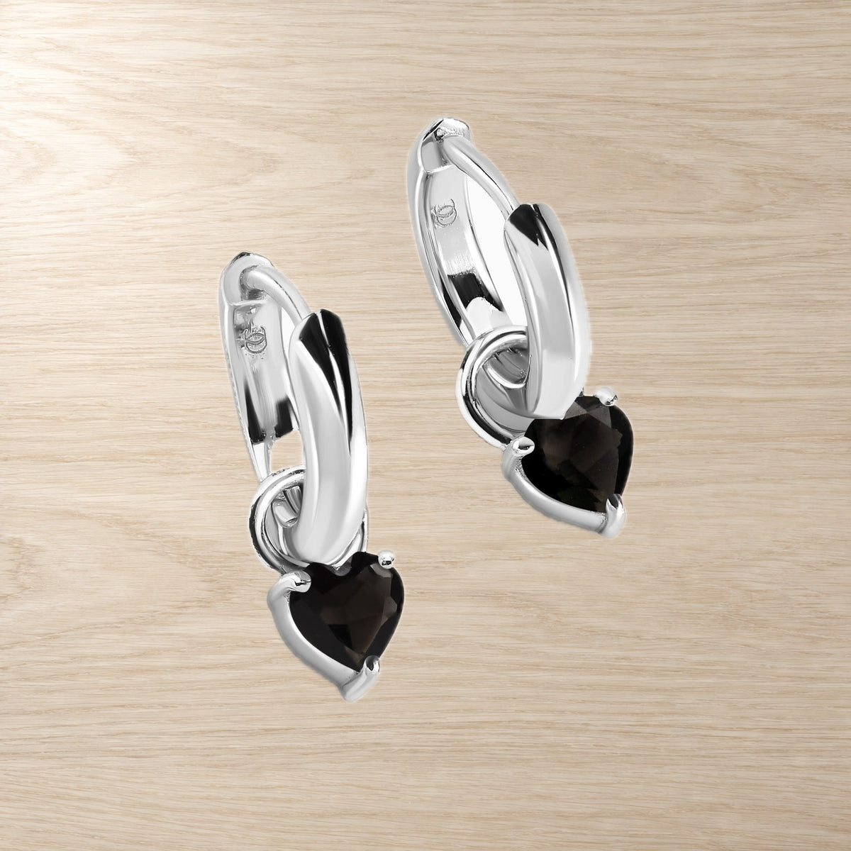 Heart-shaped black obsidian hoops photographed flat on a light surface