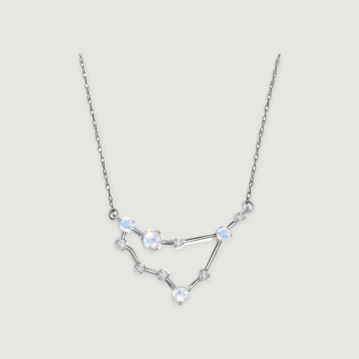 A white gold chain holds an angular pendant with four iridescent round moonstones and small clear stones.