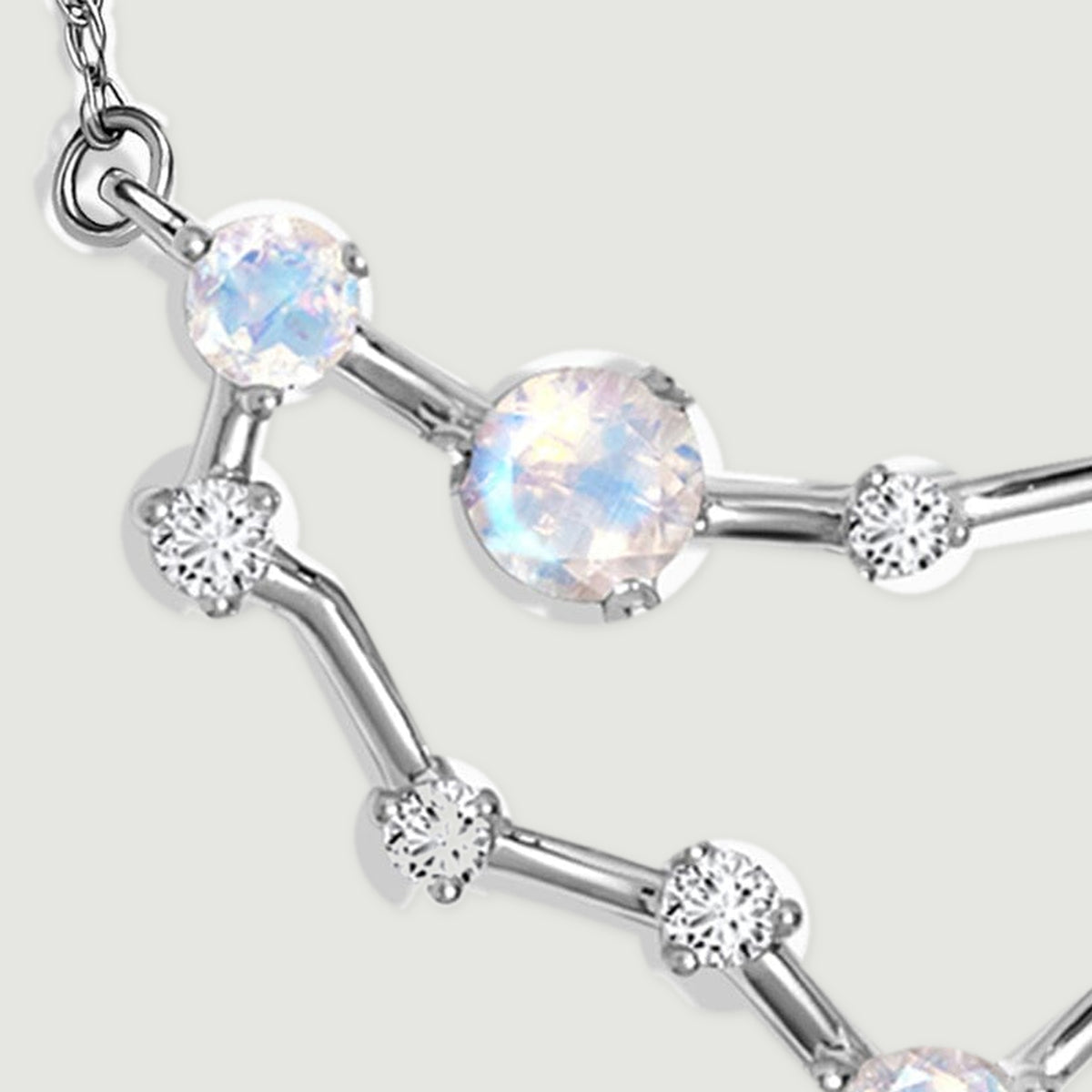 Two round moonstones sit beside polished white gold bars and small clear stones on the left of the pendant.