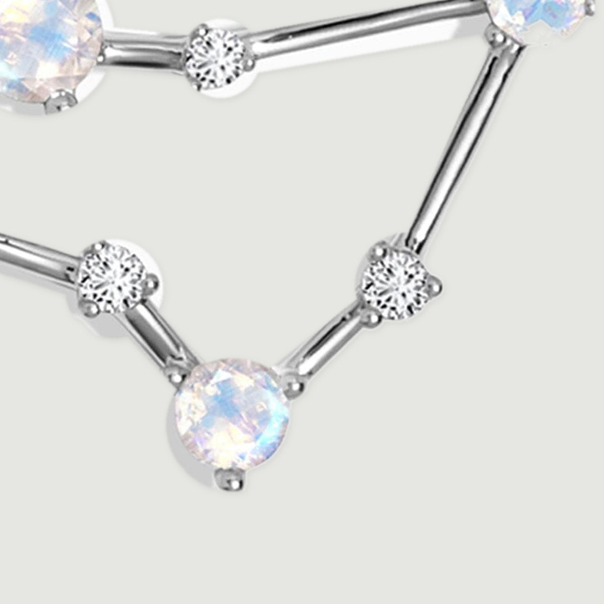 A round moonstone forms the lower point of the pendant between two small clear stones.