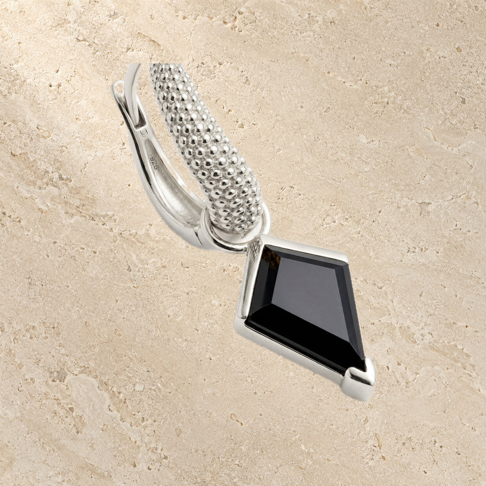 Kite-cut black obsidian hoop earring on a textured beige background
