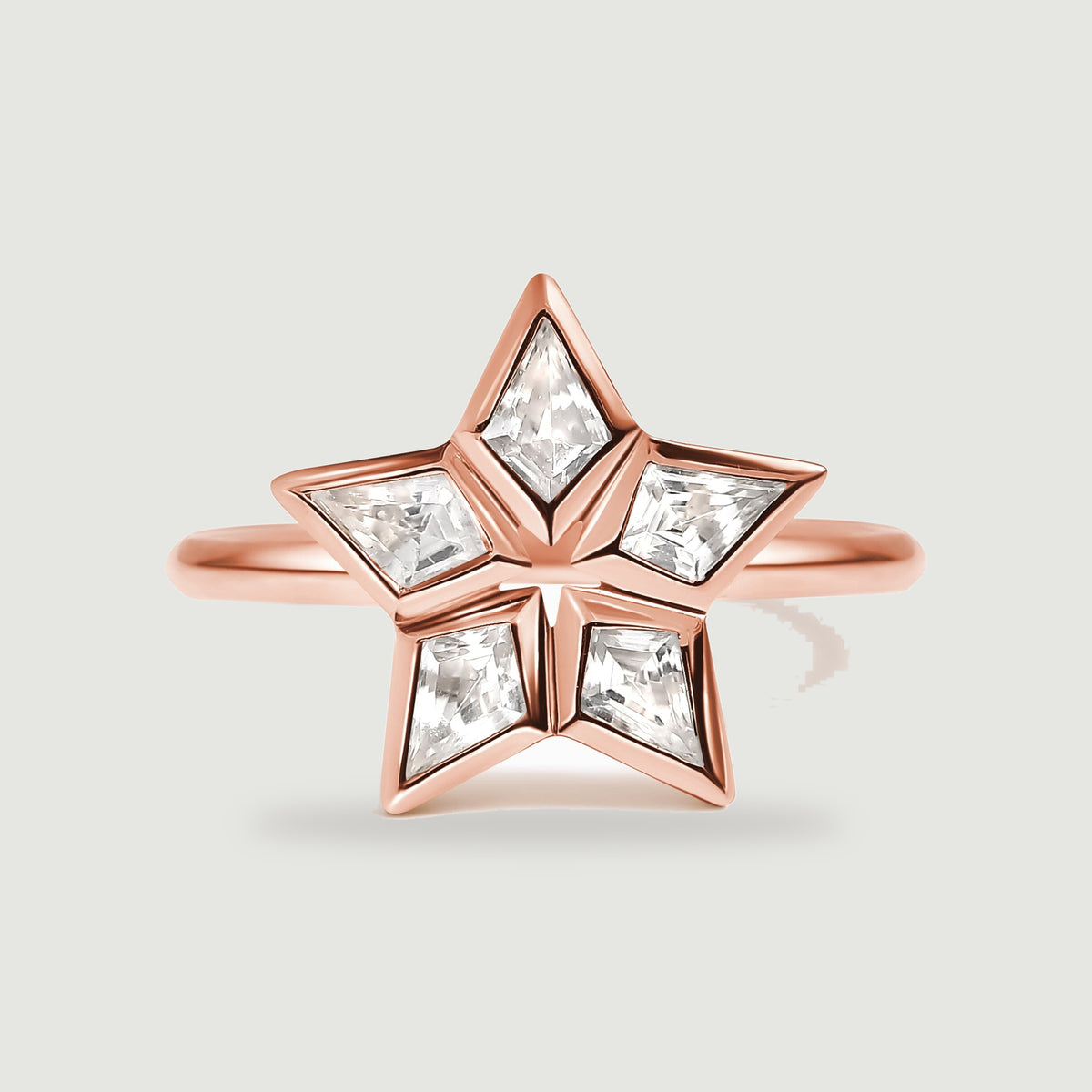 A rose gold ring has five kite-shaped clear stones arranged around an open star center.