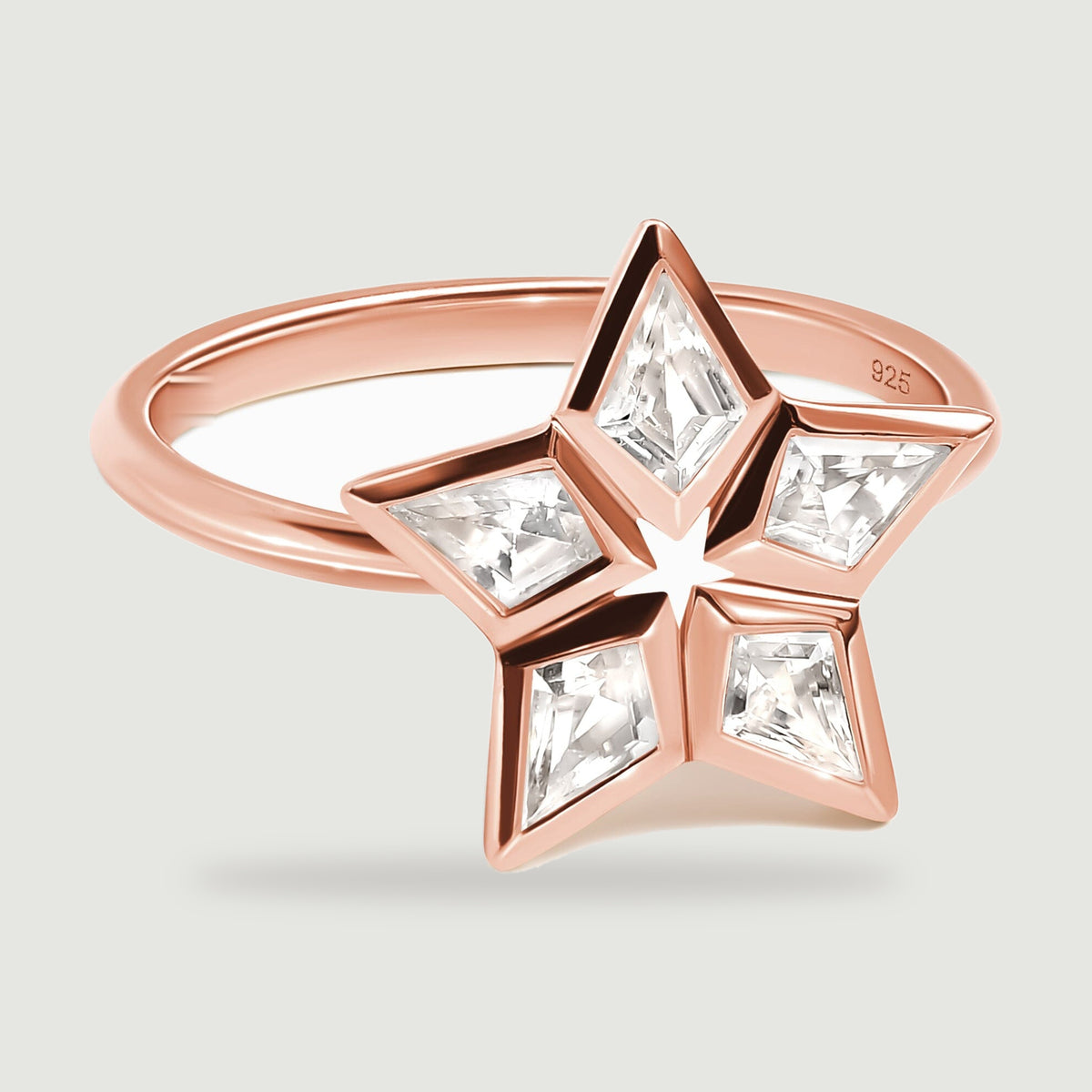 Five clear kite-shaped stones frame an open star on a rose gold ring shown at a low angle.