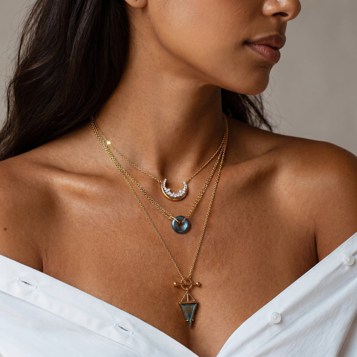 Two silver necklaces on a model's chest with a small labradorite pendant