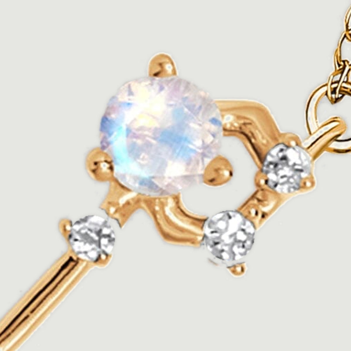 A large round moonstone sits beside three small clear stones in the curved gold setting.