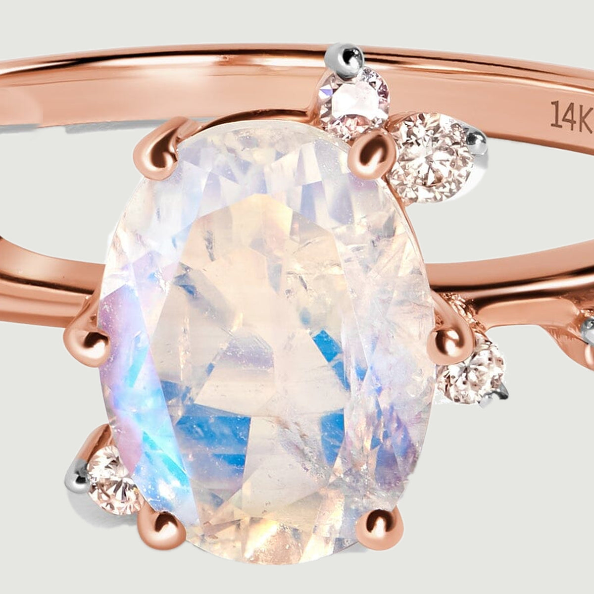 A close view shows the oval moonstone facets, rose gold claws and surrounding round diamonds.