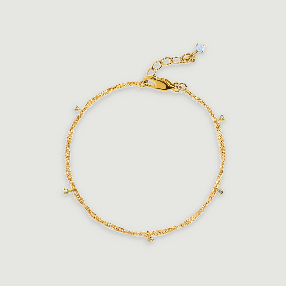 A yellow gold vermeil anklet is arranged in an oval with clear gemstone drops and a lobster clasp.