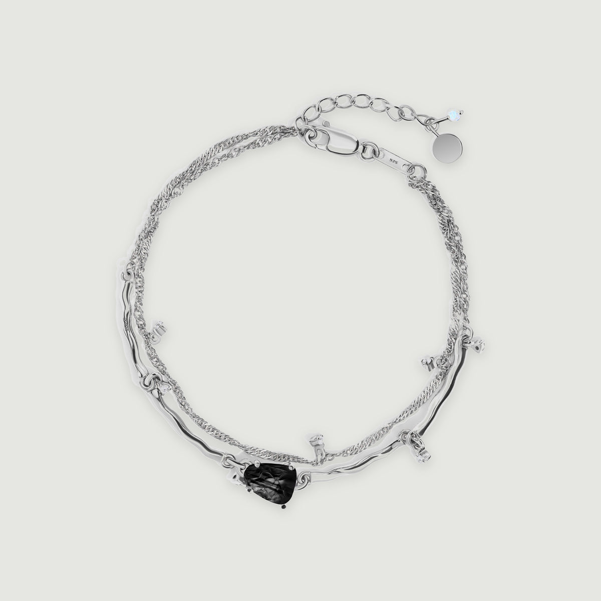 A complete silver bracelet with a black irregular stone, curved links, a fine chain, and an extender rests on light gray.