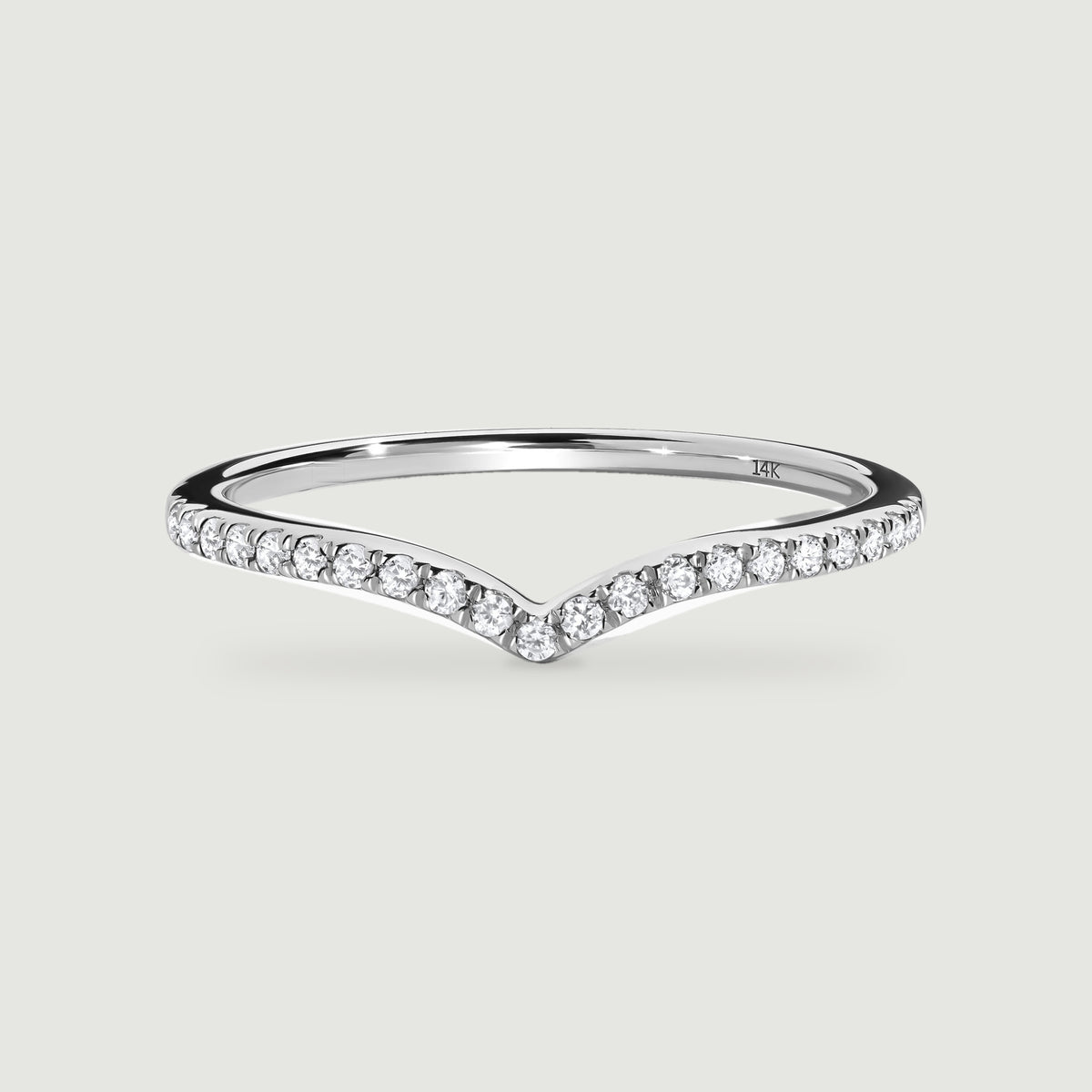 A white gold ring displays a continuous row of round diamonds along its angled front edge.