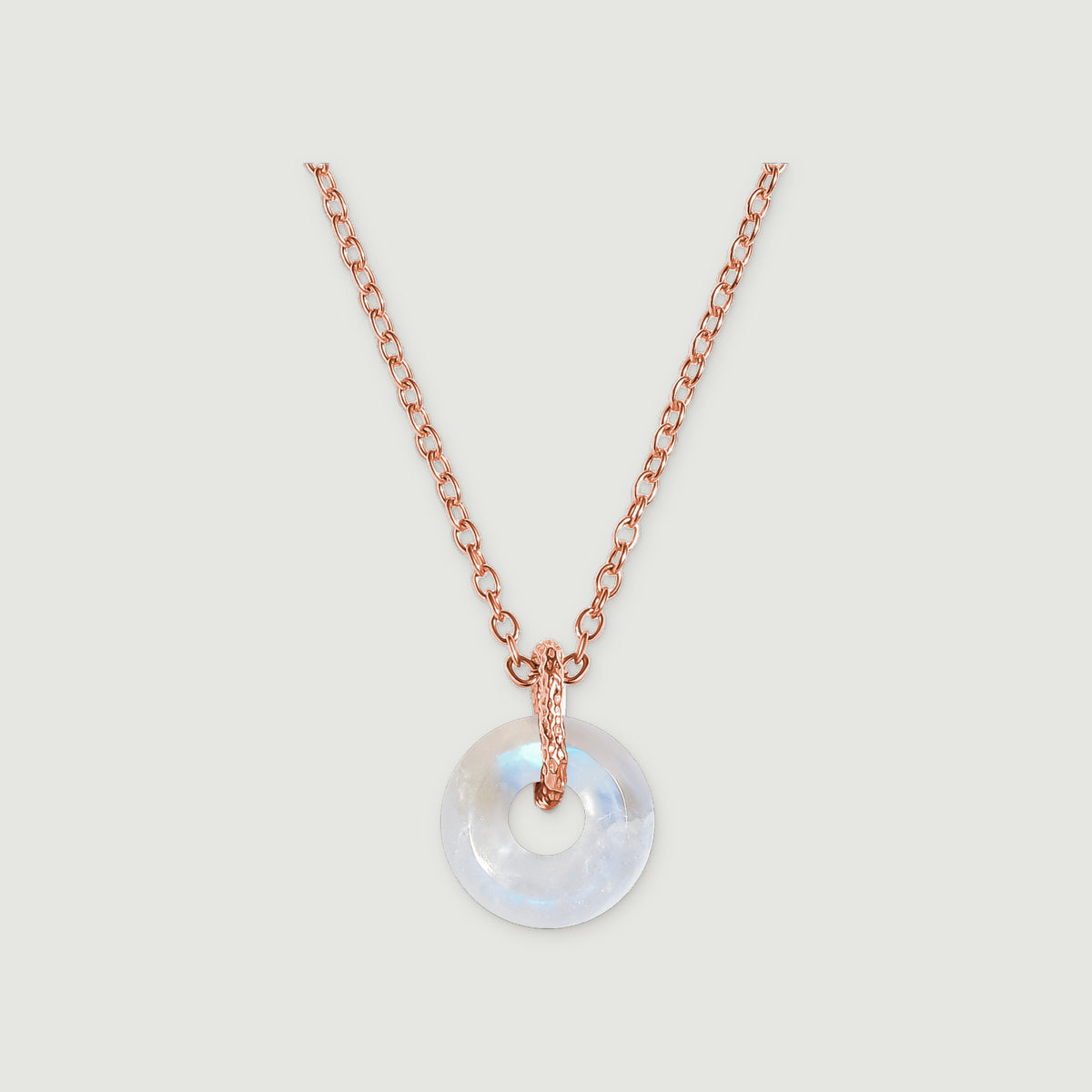 A circular moonstone pendant hangs from a rose gold chain against a light gray background.
