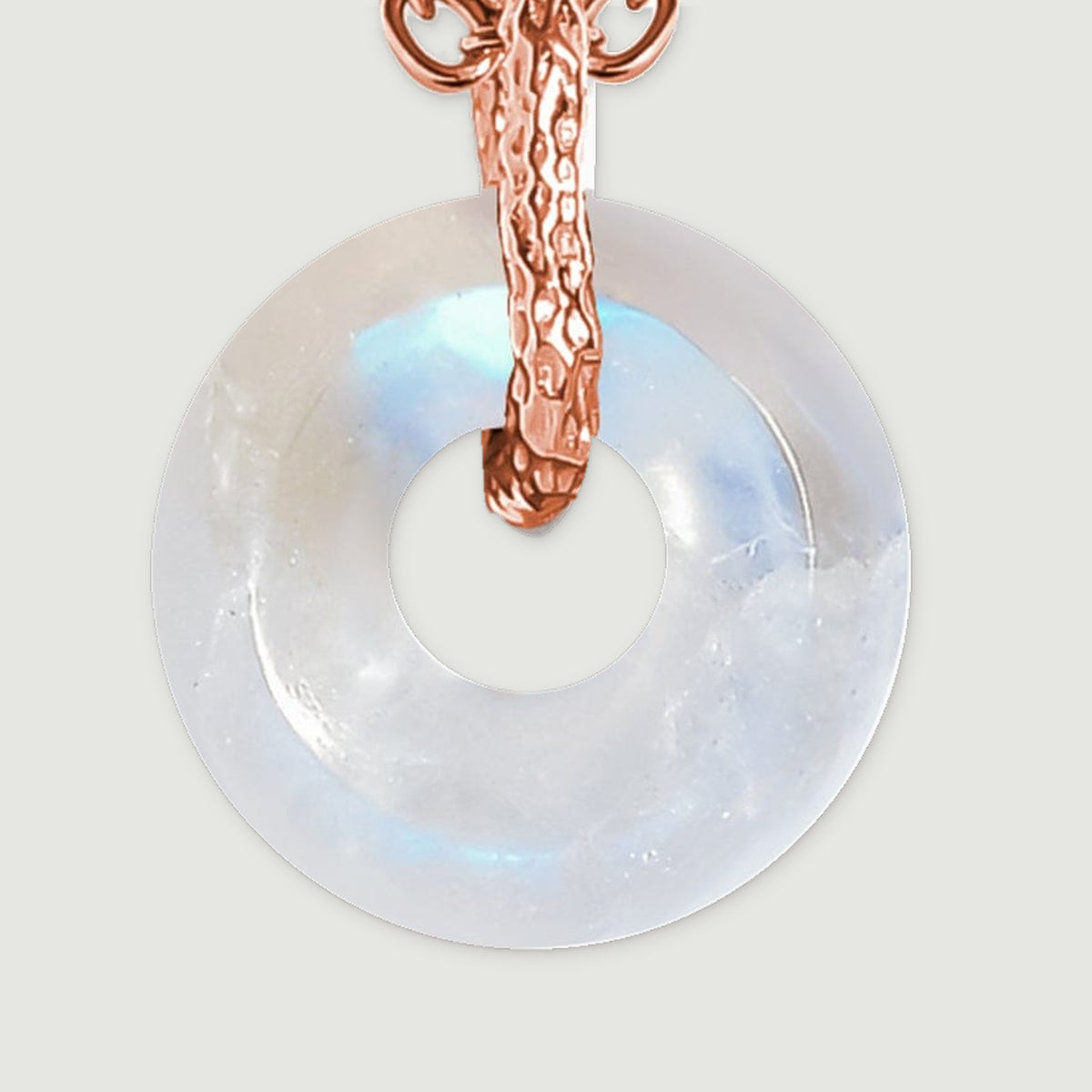 A pale moonstone disc shows blue reflections around its central opening beneath a textured rose gold bail.
