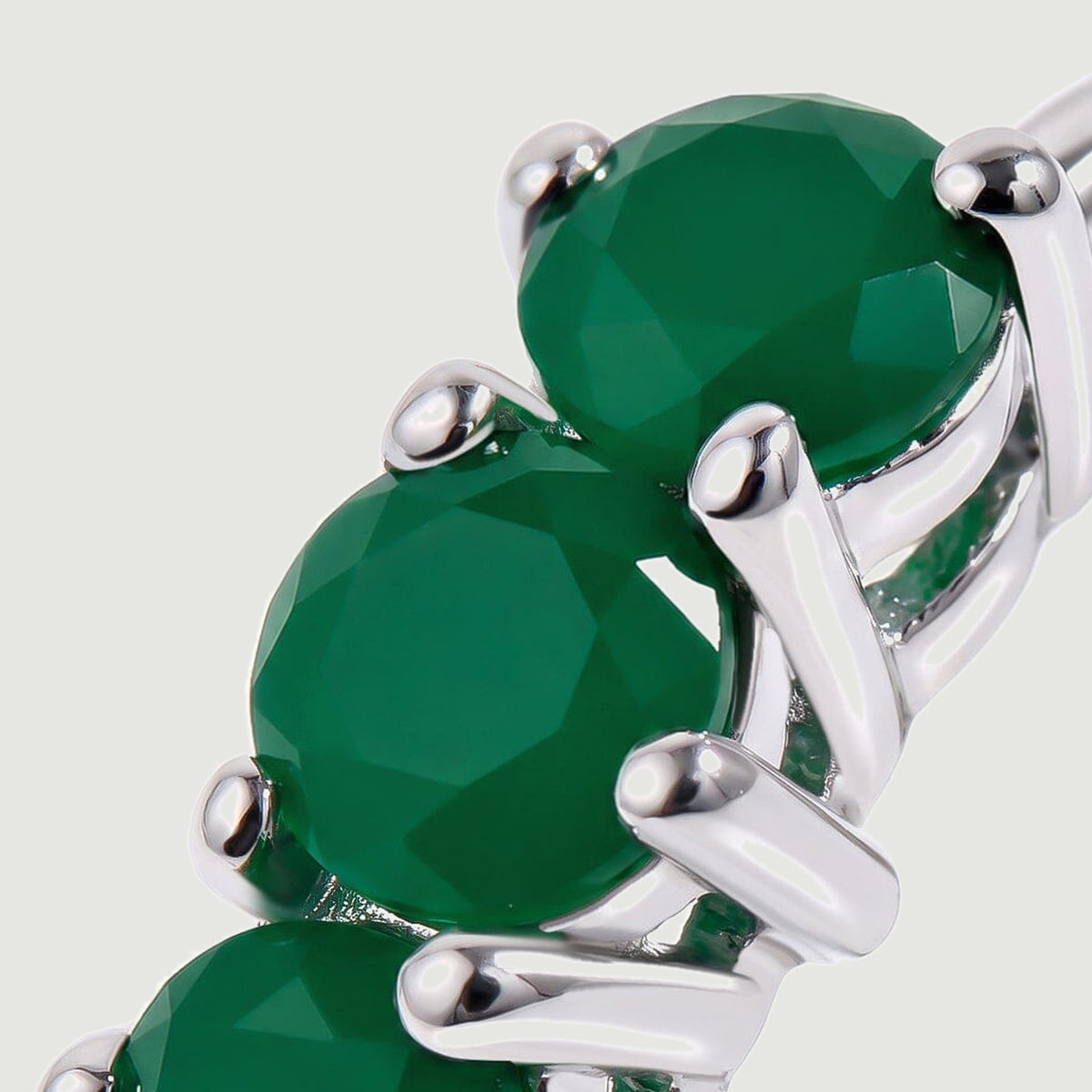Round green gemstone facets and bright silver colored prongs fill this close view.