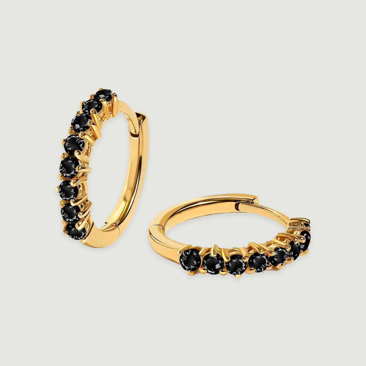 Two yellow gold plated hoop earrings display round black stones against a pale gray background.