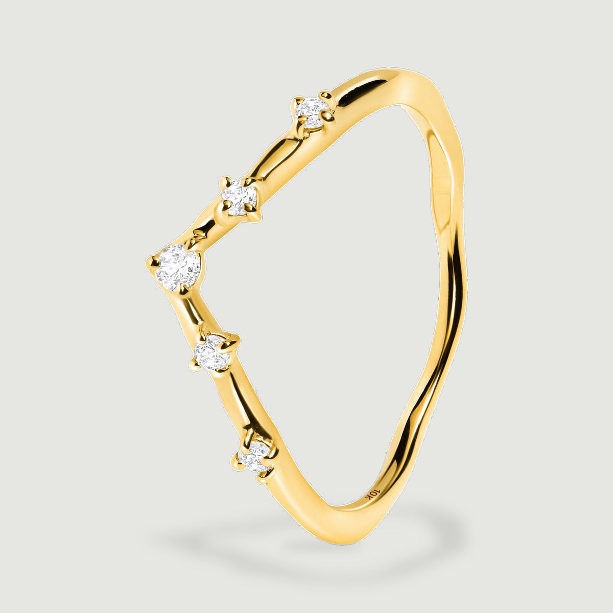 An upright yellow gold ring reveals the staggered round diamonds and the slender curved band from an oblique angle.