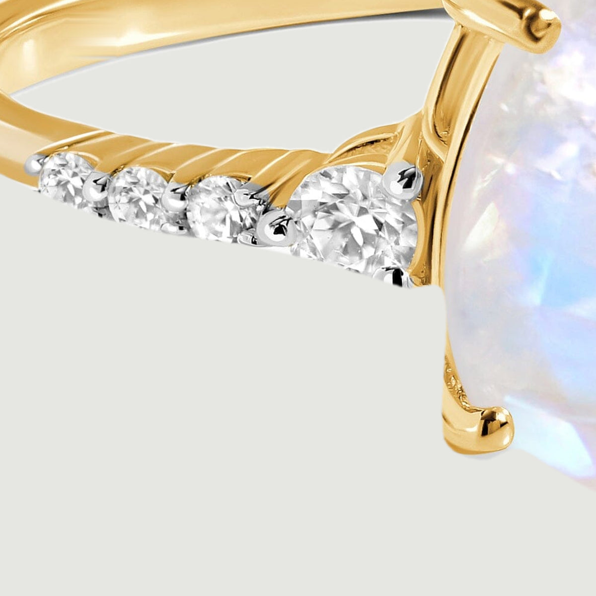 Round diamonds graduate in size along the yellow gold shoulder beside the moonstone.
