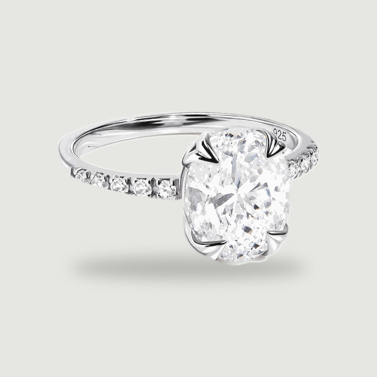 A complete sterling silver ring with an oval clear faceted stone and small stones along the shoulders rests on a light gray background.