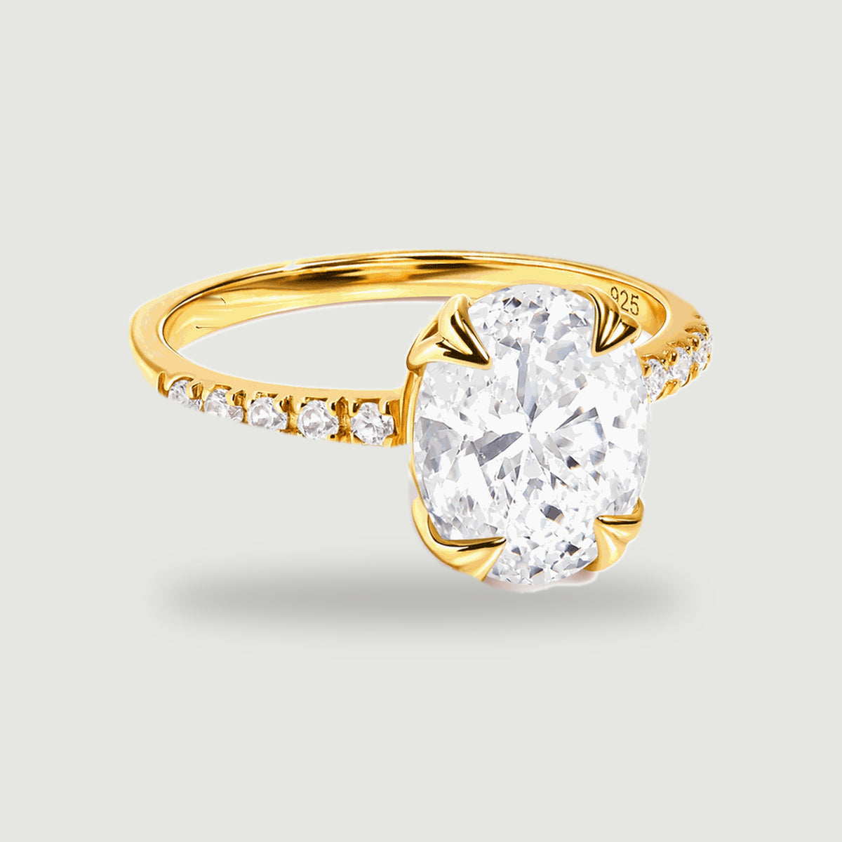 A complete yellow gold vermeil ring with an oval clear faceted stone and small stones along the shoulders rests on a light gray background.