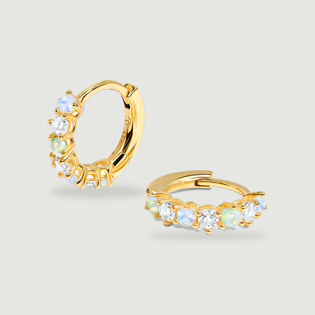Two yellow gold vermeil hoops display alternating blue, green and clear round stones against pale grey.