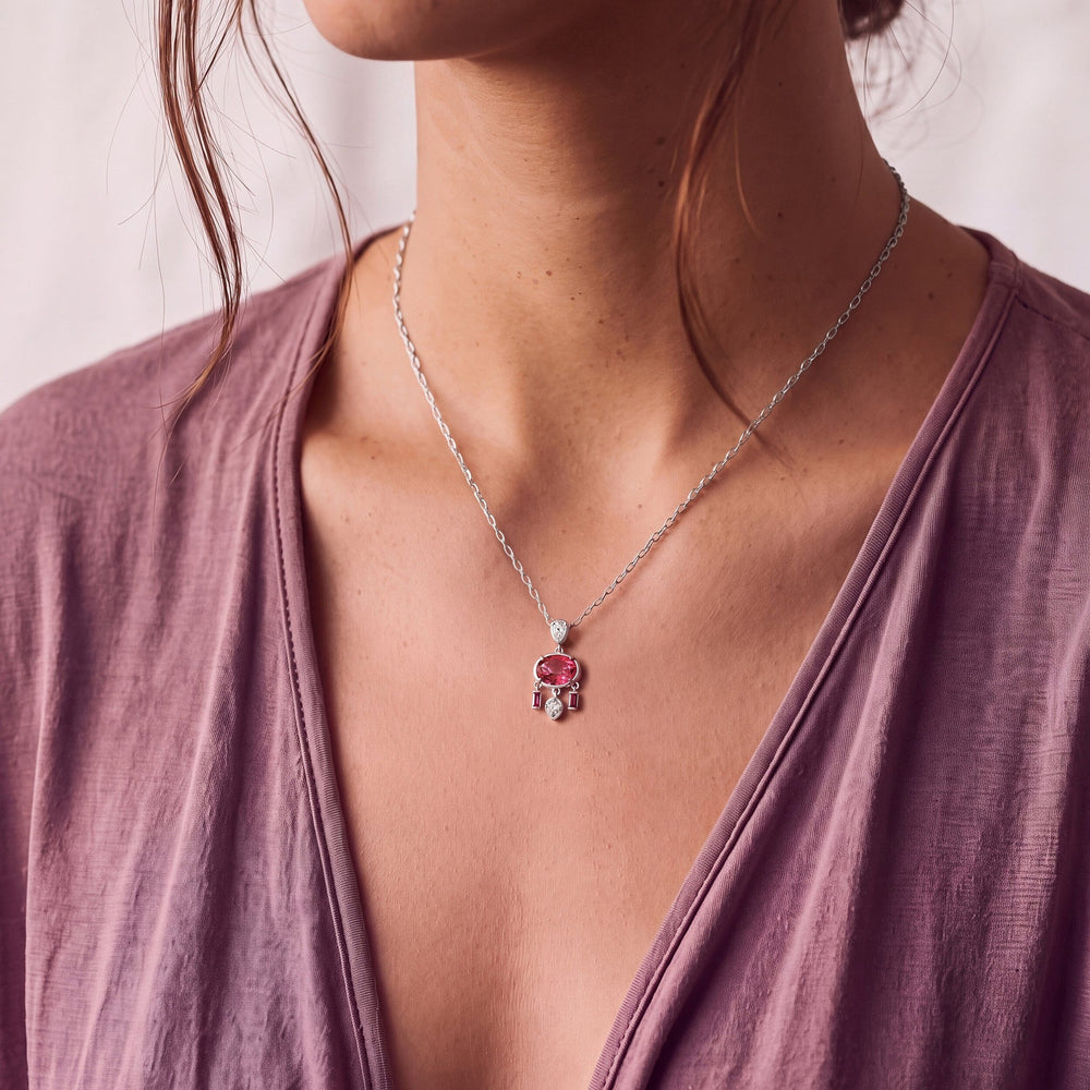 Pink topaz pendant worn at the neckline of a mauve top