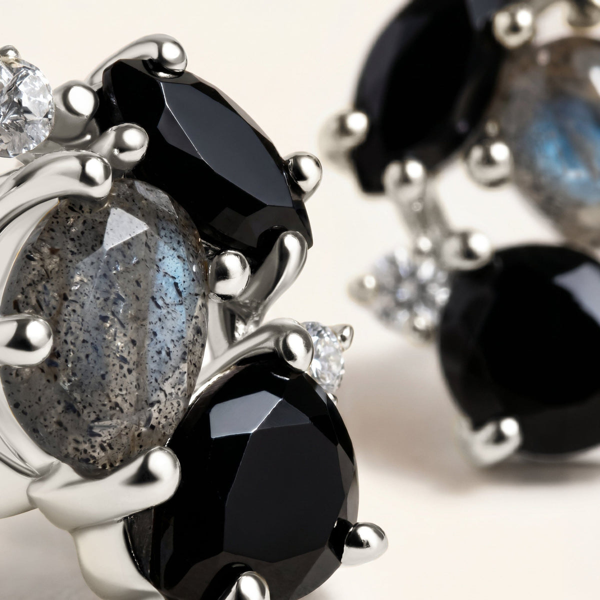 A close view reveals silver prongs around a speckled labradorite stone beside glossy black facets.