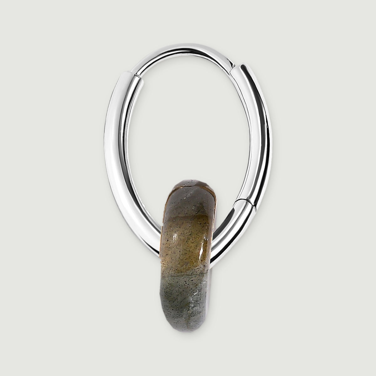 The side of a silver-tone earring reveals its curved hoop, hinged section and smooth gray stone edge.