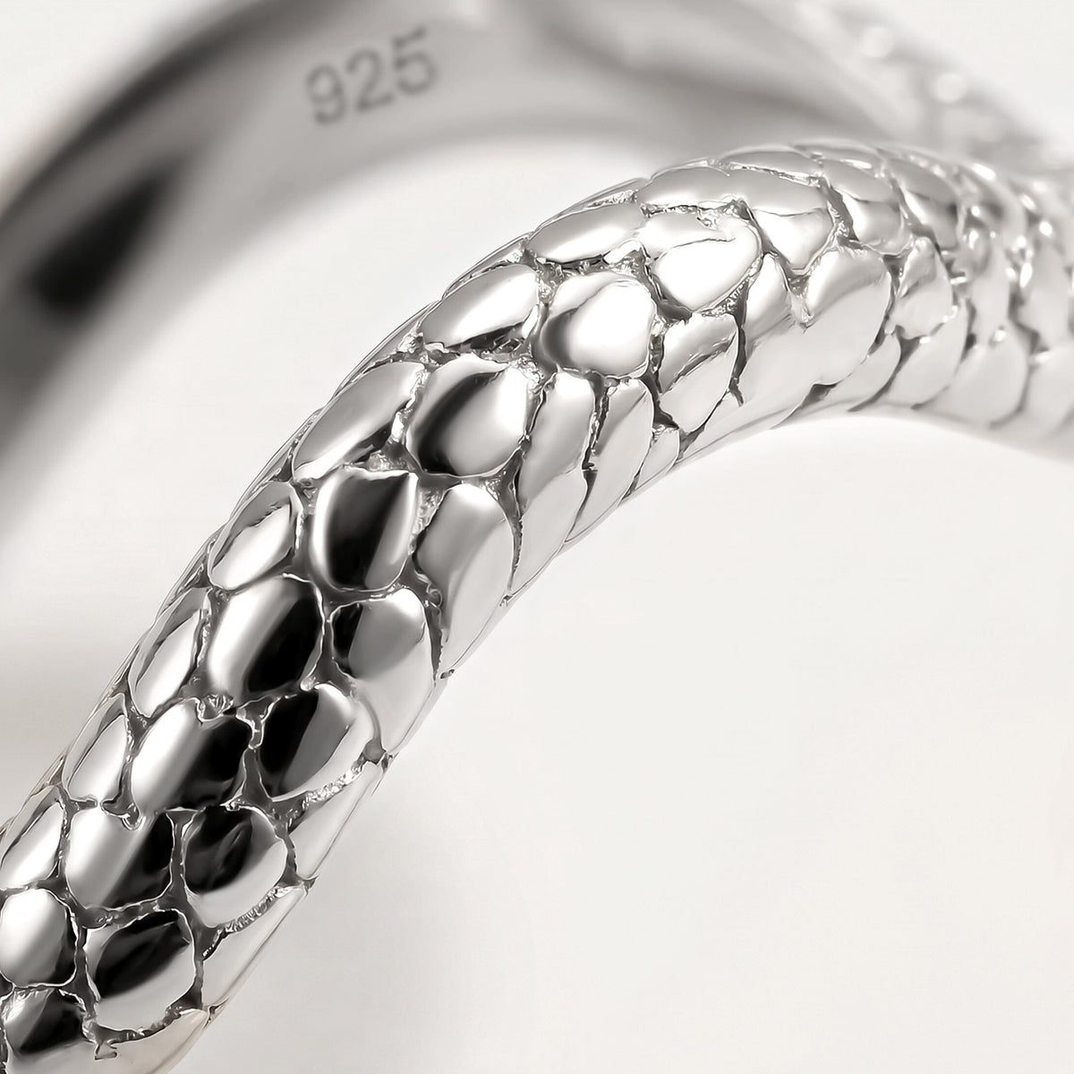 A close view shows polished oval details and dark recessed lines along the silver band.