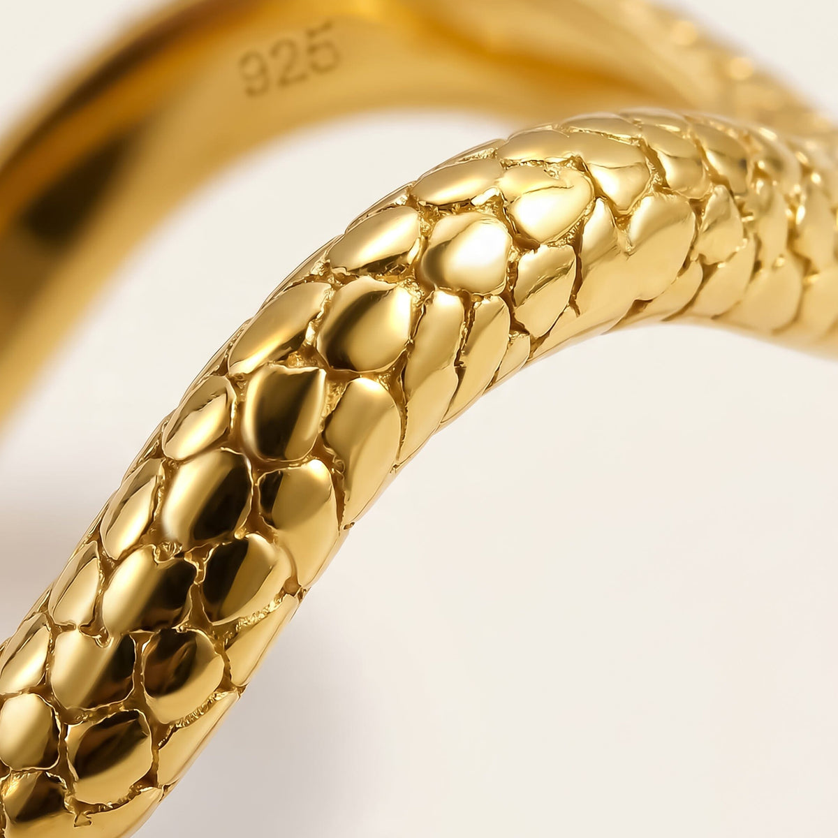 The yellow gold band fills the frame with rounded raised details and bright reflections.