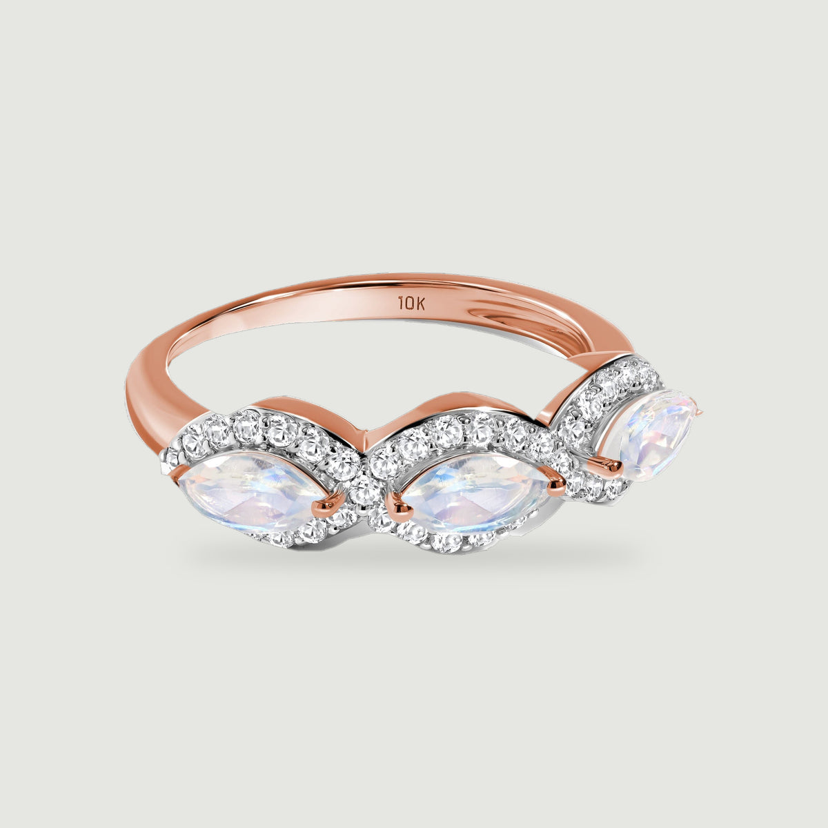 A rose gold ring shows three translucent moonstones, polished prongs and clear diamond borders.