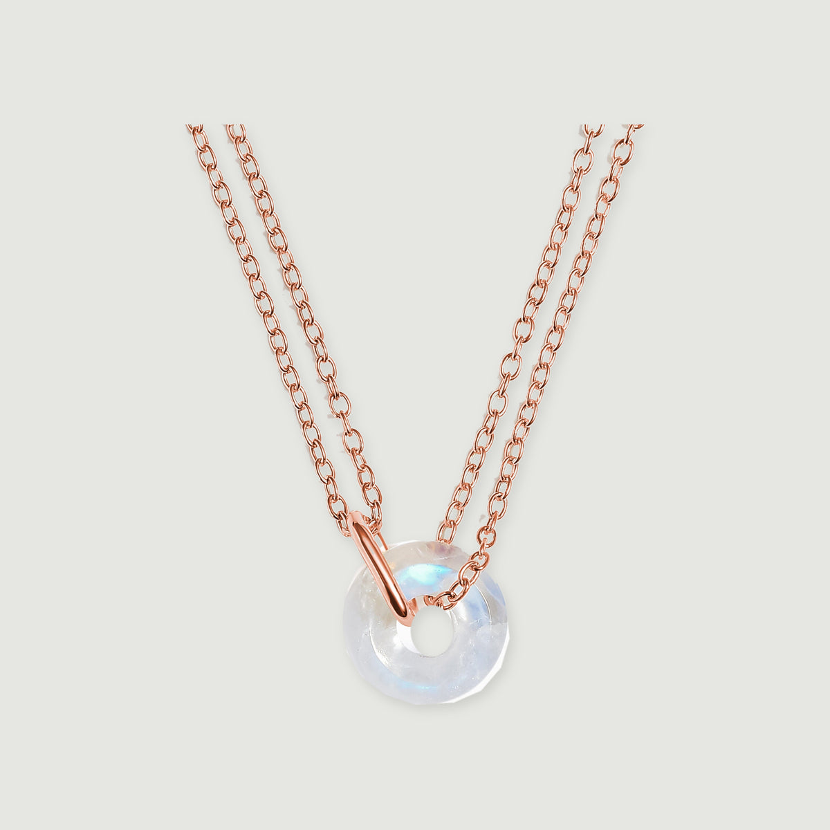 A rose gold vermeil double chain passes through a polished connector beside a round moonstone pendant.