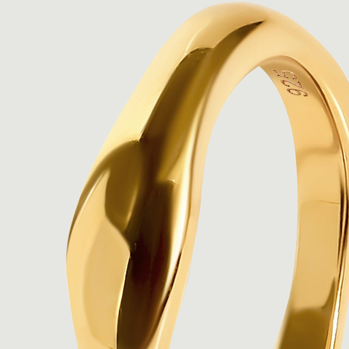The upper shoulder of the yellow gold vermeil ring curves from its broad polished face into the narrow band.