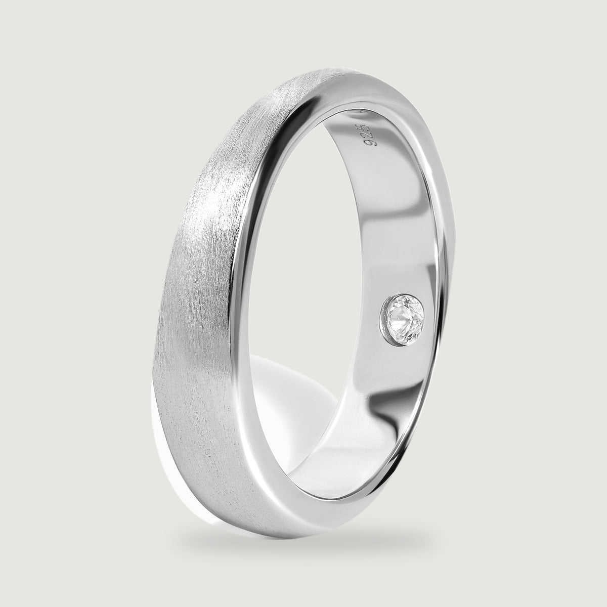The silver band stands at an angle, showing its rounded profile and polished inner surface.