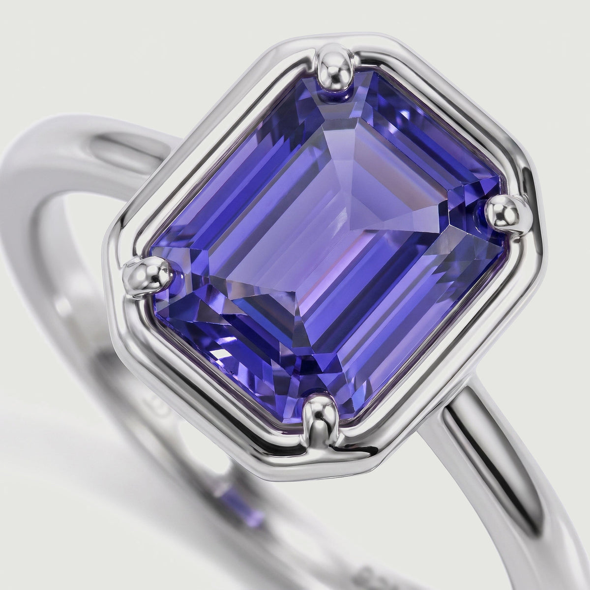 A close angled view reveals a violet rectangular gemstone and its polished silver setting.