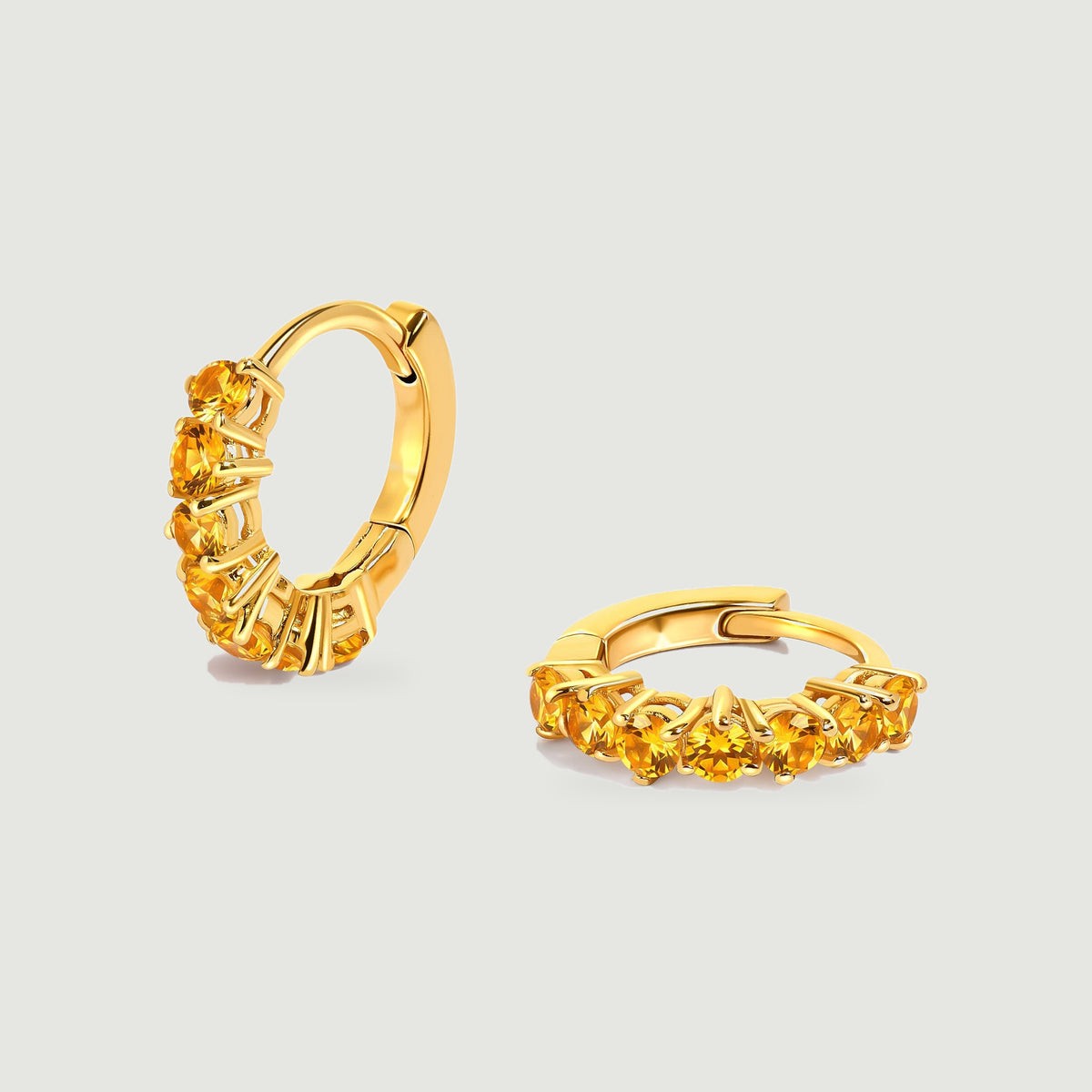 Two gold-tone citrine hoop earrings show round amber stones against a light gray background.