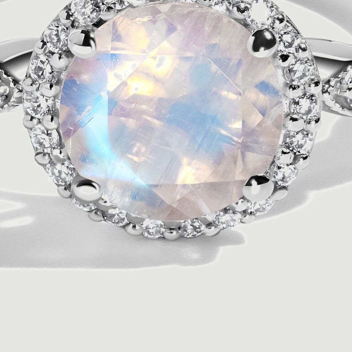 A close view of the white gold setting reveals the moonstone facets, four prongs and small diamonds around the halo.