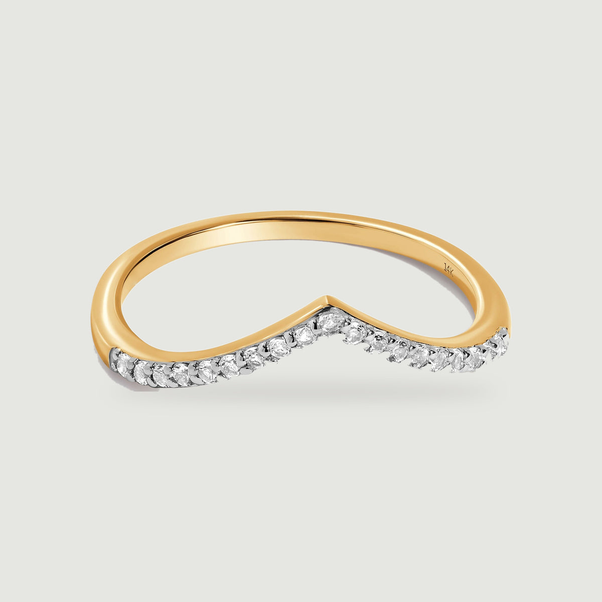 A yellow gold ring with a diamond-set V-shaped front rests above a soft contact shadow.