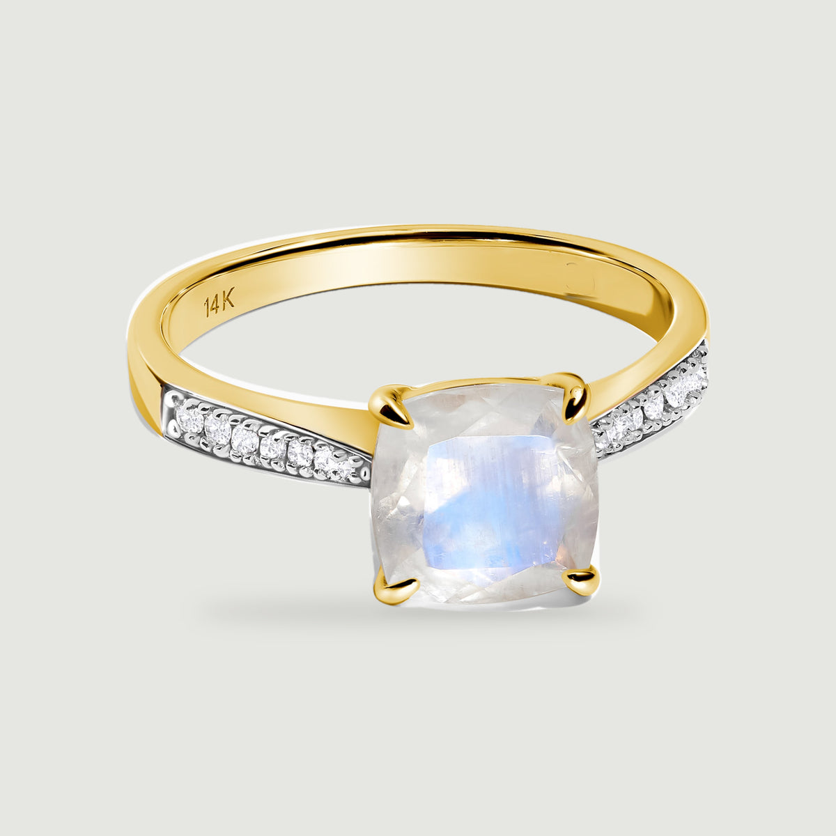 A yellow gold ring with four rounded prongs surrounds a pale moonstone above diamond-set shoulders.